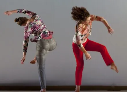 two dancers bend and reach away from each other