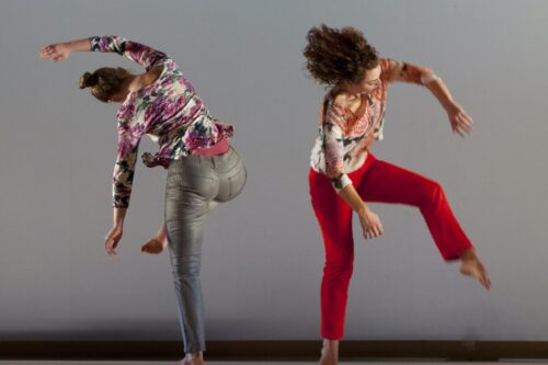 two dancers bend and reach away from each other