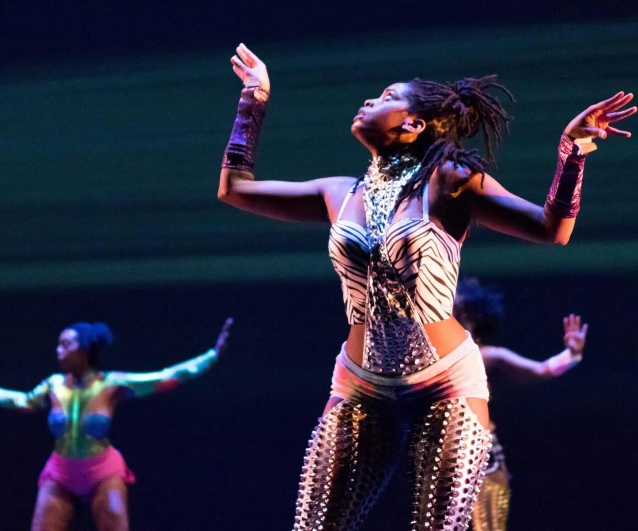 Dancer holds both arms up as she gazes upward