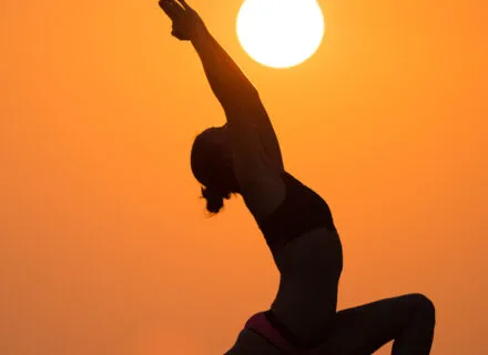 A yoga pose with the sun in the distance