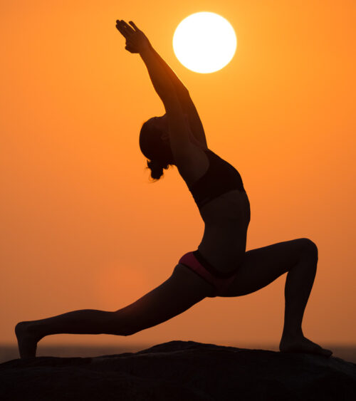 A yoga pose with the sun in the distance