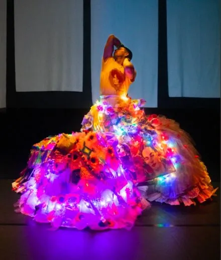 Dancer with huge flowing, lit skirt. Arms upstretched