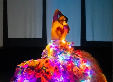 Dancer with huge flowing, lit skirt. Arms upstretched