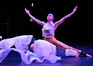 a dancers kneels with her arms outstretched