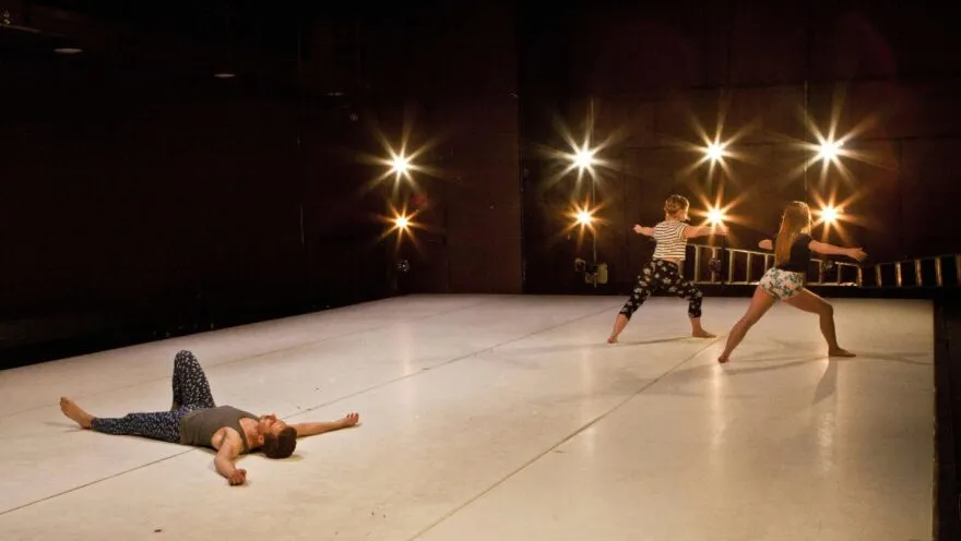 dancer on the floor with two other dancers standing in the corner