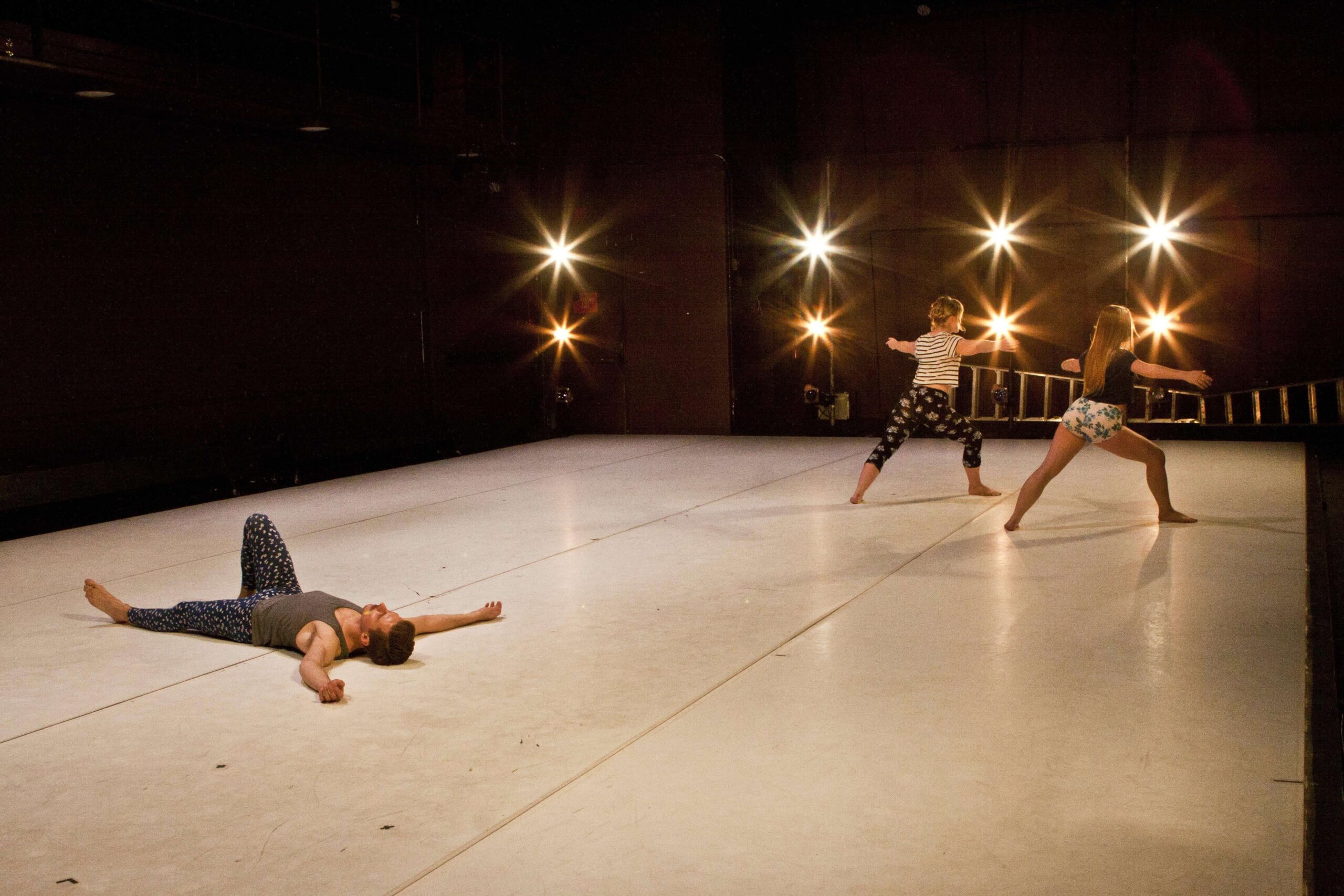 dancer on the floor with two other dancers standing in the corner