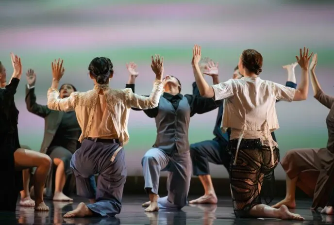 dancers crouch in a huddle with their arms up