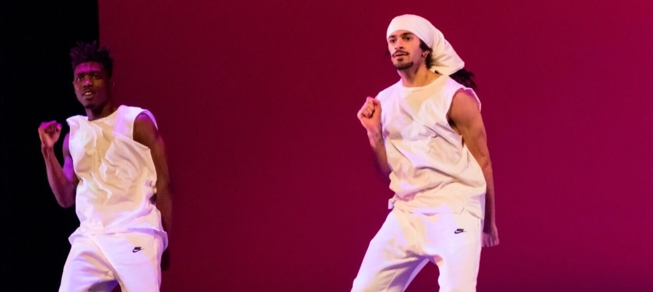 two dancers in front of pink lighting