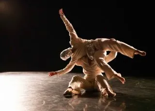 one masked dancers being lifted by another
