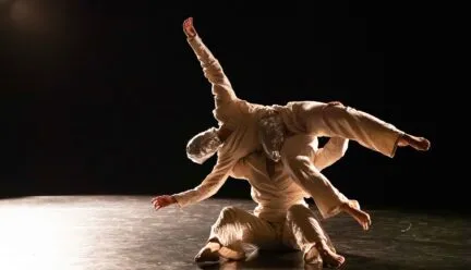 one masked dancers being lifted by another