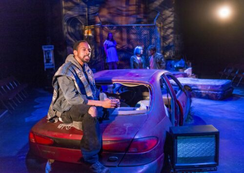 Young person sitting on trunk of car in Studio Theatre production