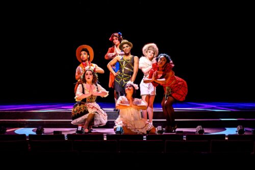 Two costumed performers stand center stage