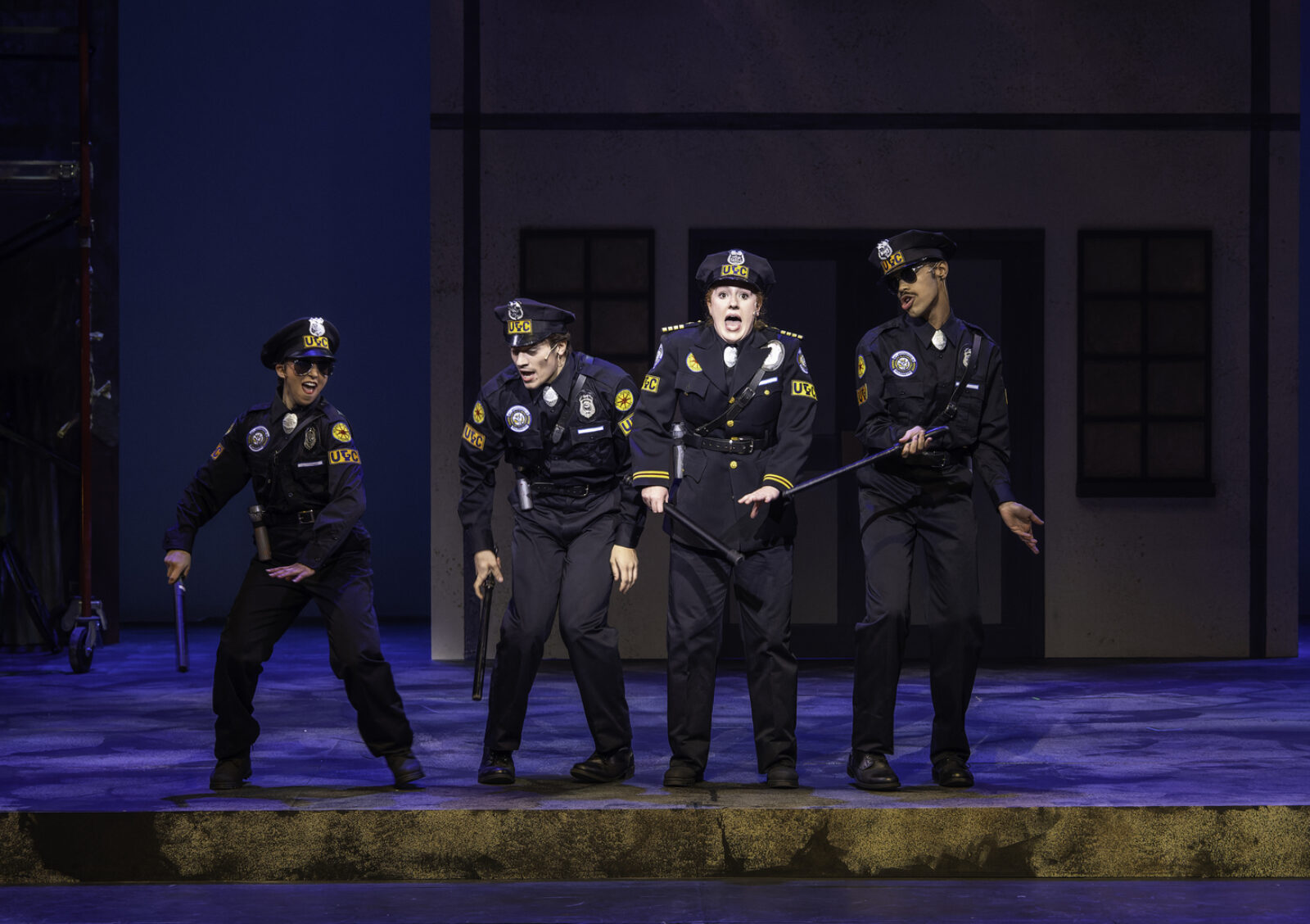 4 actors on stage in police costumes