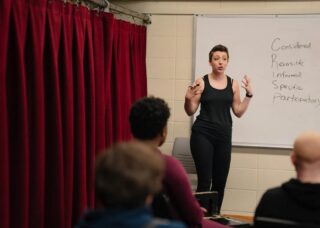 jessica steinrock stands in front of whiteboard in a classroom at Krannert Center teaching students about consent in theatre, film, and television