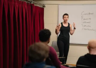 jessica steinrock stands in front of whiteboard in a classroom at Krannert Center teaching students about consent in theatre, film, and television