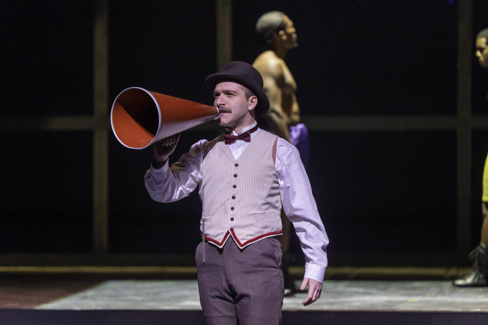 actor on stage speaks through a megaphone