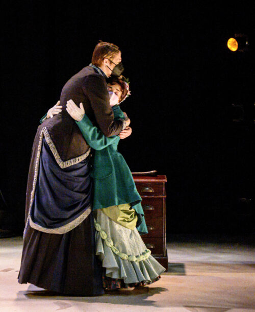 2 actors on stage hugging in costume