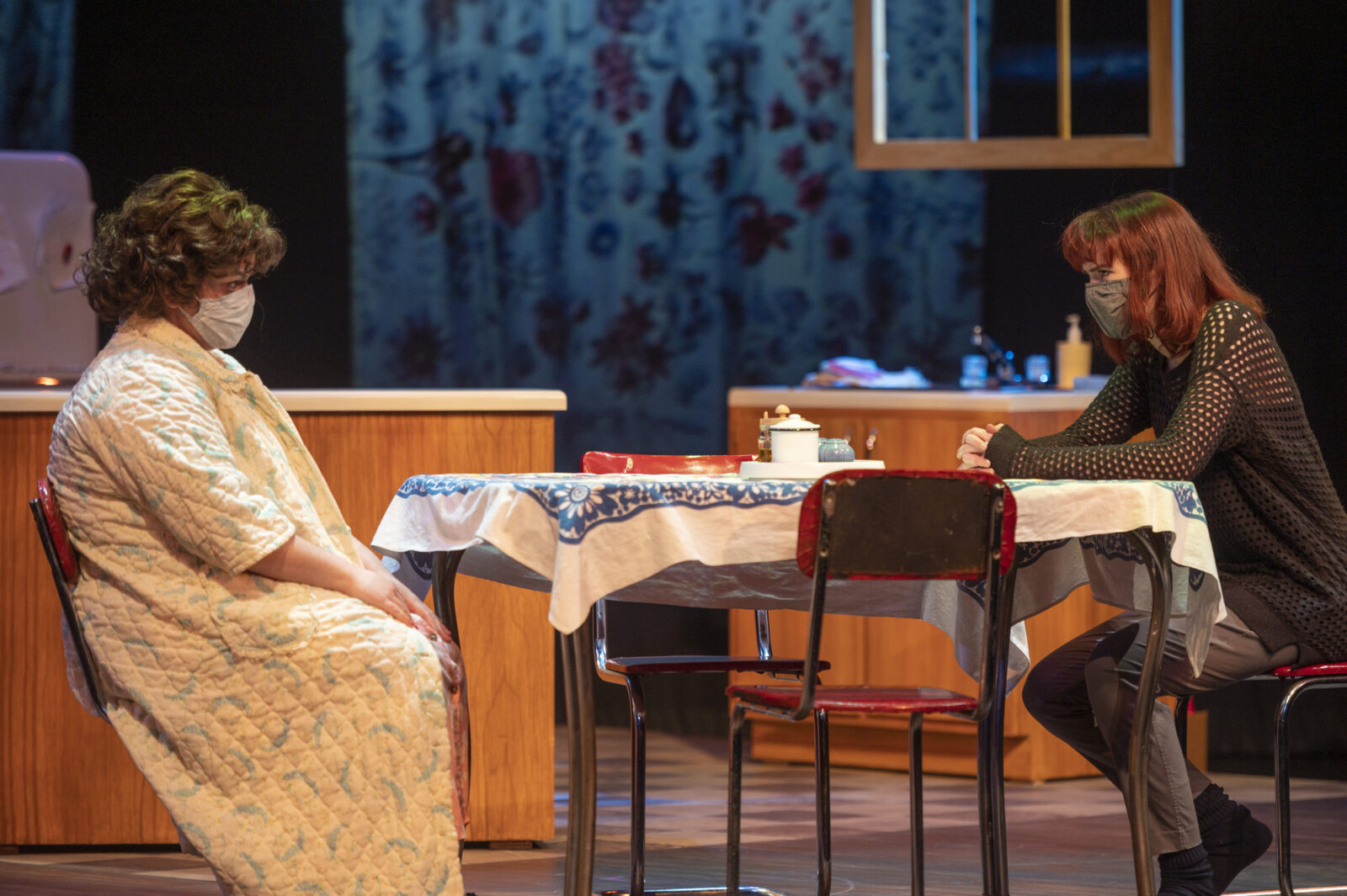 two people sit at a table on stage