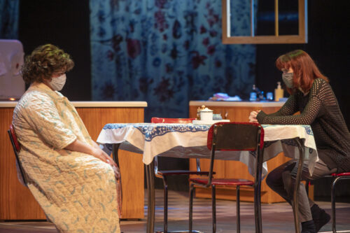 two people sit at a table on stage