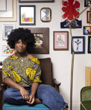 person sits on chair surrounded by artwork on the walls