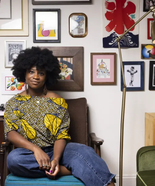 person sits on chair surrounded by artwork on the walls
