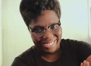 person with arms crossed, smiling at the camera 