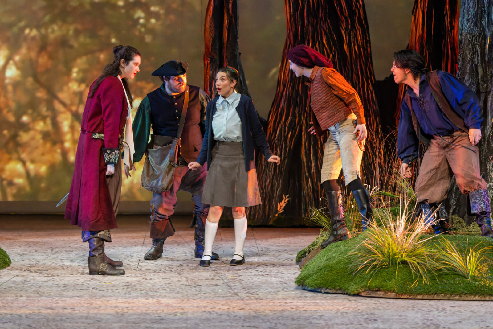 actors onstage with bright lights and scenic trees