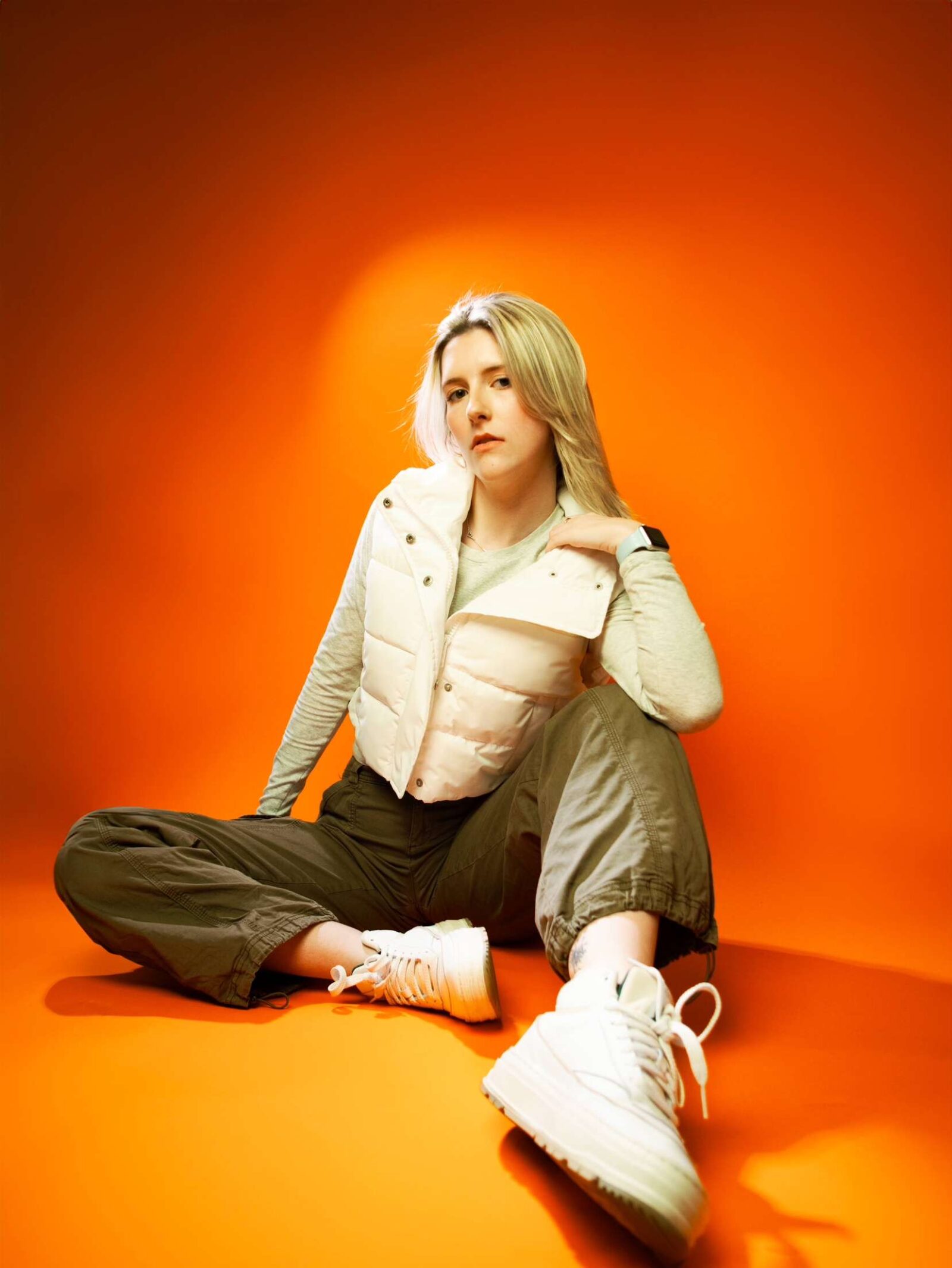 courtney sitting wearing a vest and sneakers