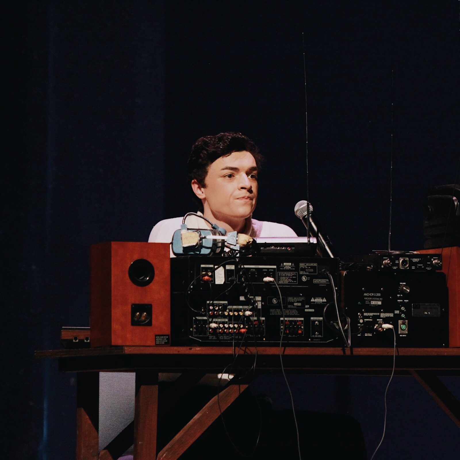 actor on stage in front of mic and large recording machinery