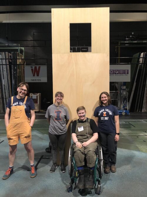 people smiling standing in front of a large wooden dumbwaiter