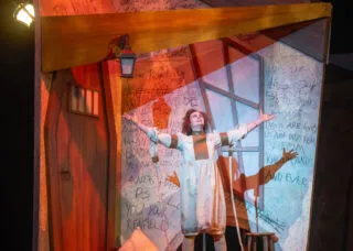 person on stage with arms outstretched