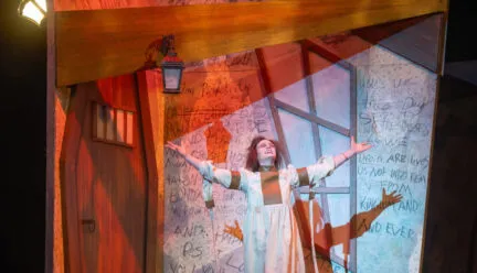 person on stage with arms outstretched