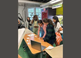 several students together looking at table with game items