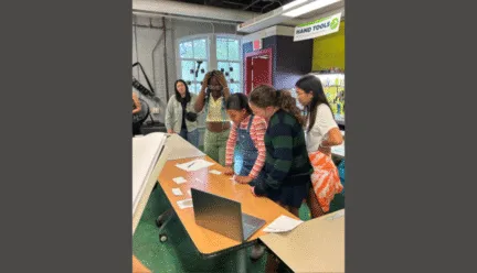 several students together looking at table with game items