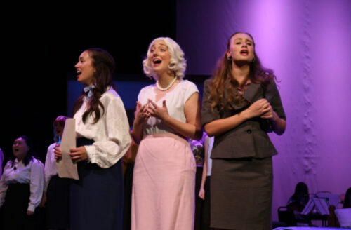 three people singing onstage together