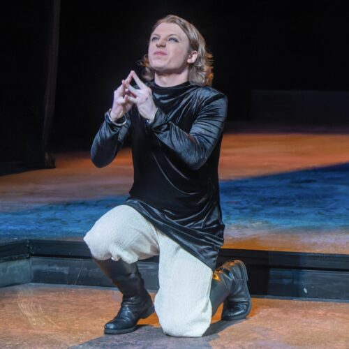 a person kneeling with hands in prayer-like position