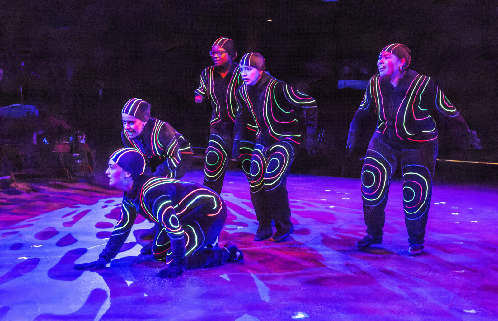 several people onstage in glow in the dark costumes