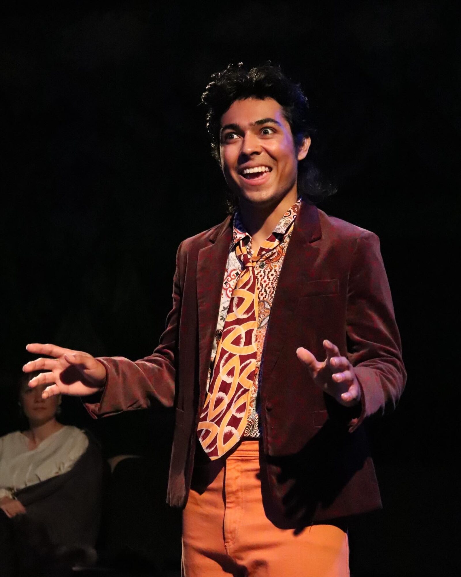 person standing smiling with arms gesticulating