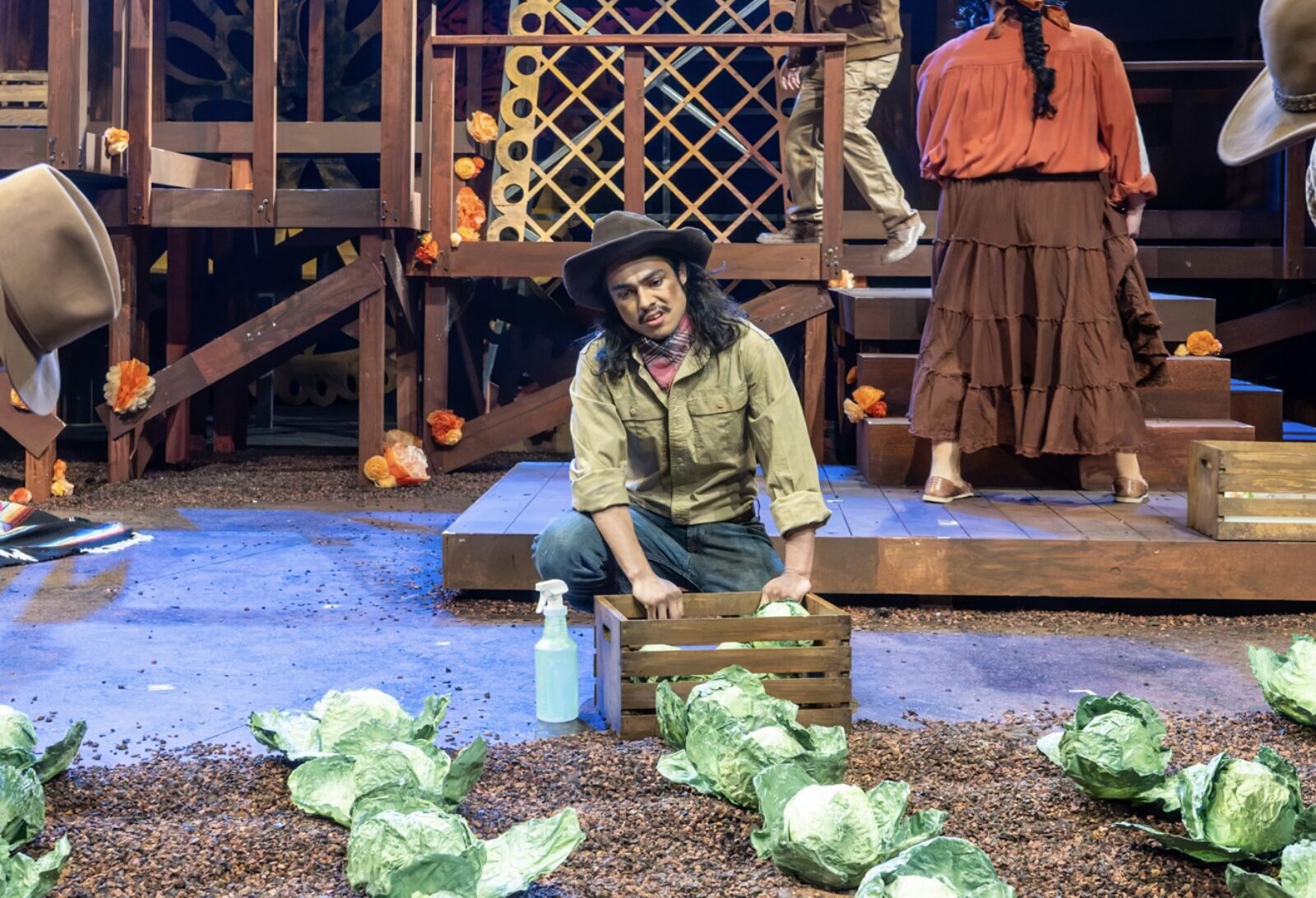 a person onstage holding a crate and picking lettuce