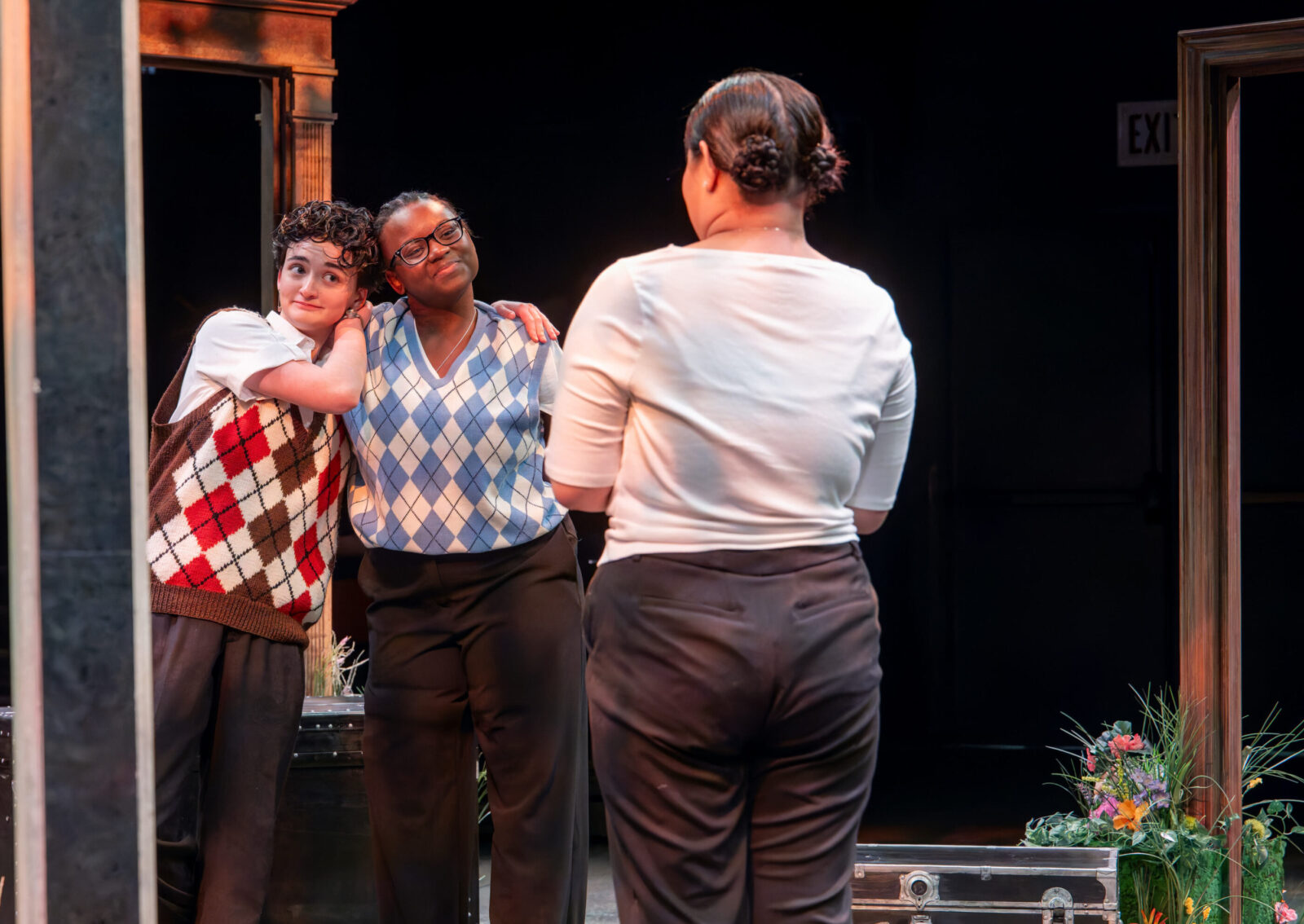 three people onstage, one is hugging another