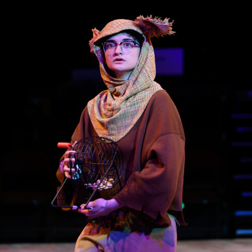 a person onstage holding a bingo cage