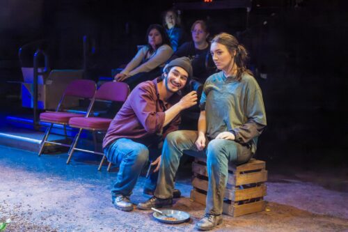 two people sitting on crates during a black box performance