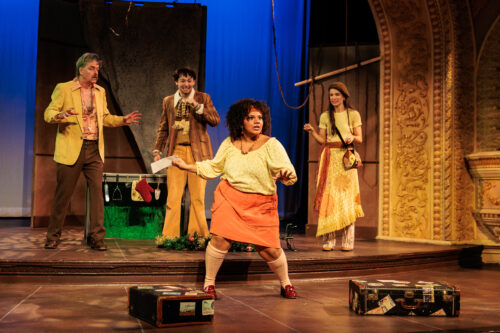 several people onstage with suitcases dancing