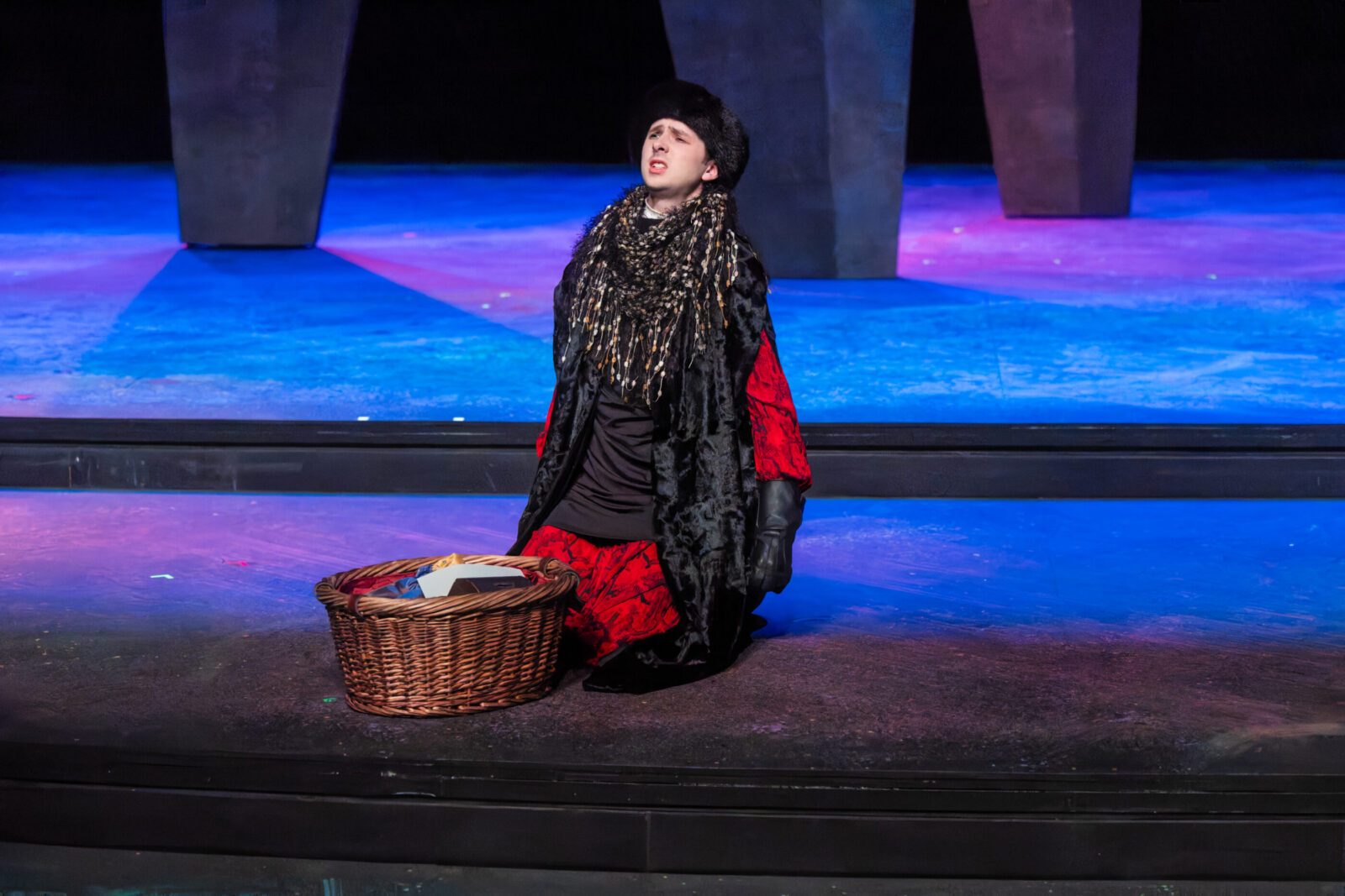 person kneeling with basket in front of them onstage