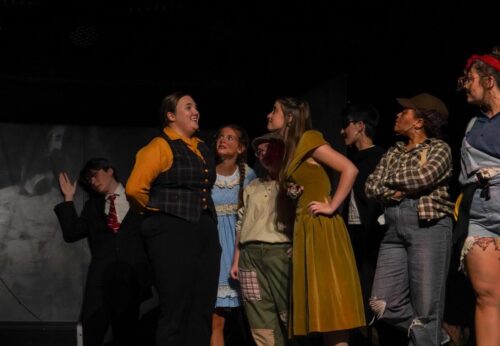 a person wearing a hat and jean vest holds out a pool cue like they are about to use it