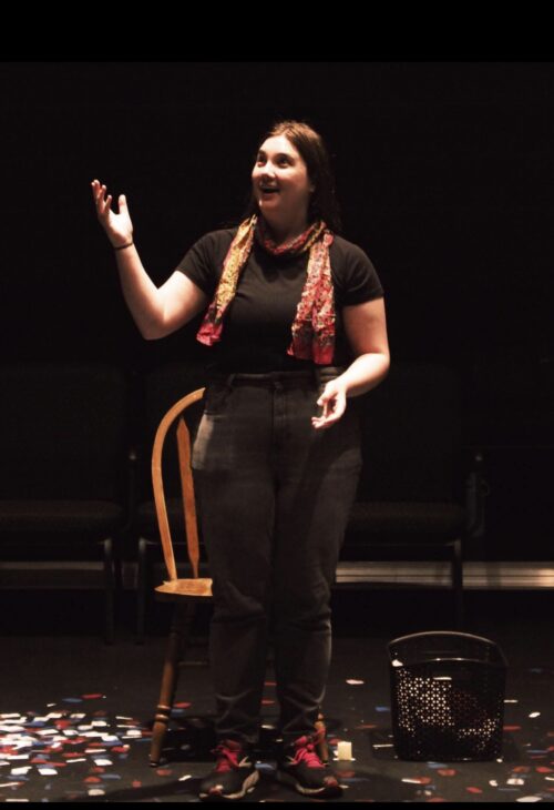 a person onstage holding a crate and picking lettuce
