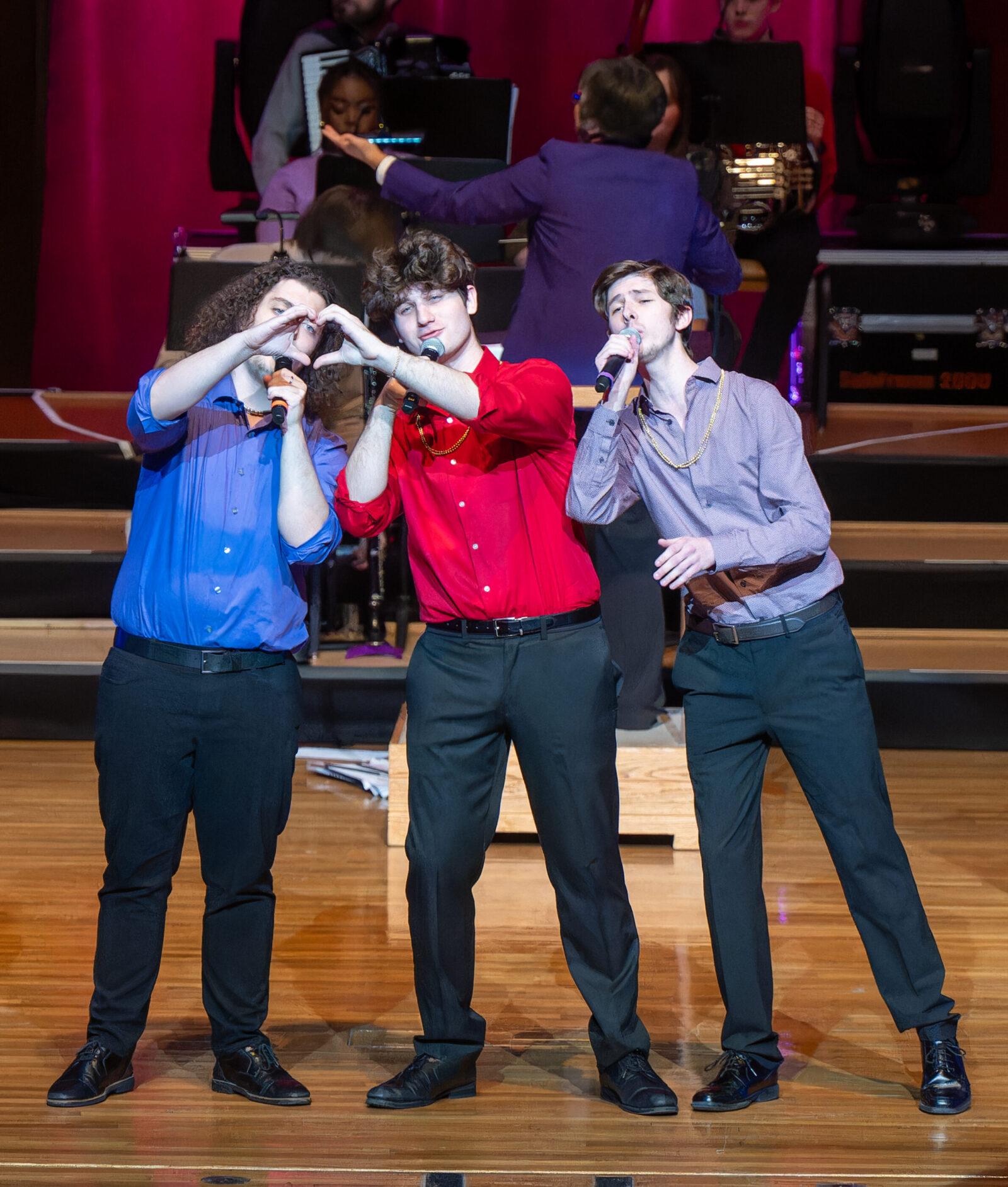 three people singing into mics onstage