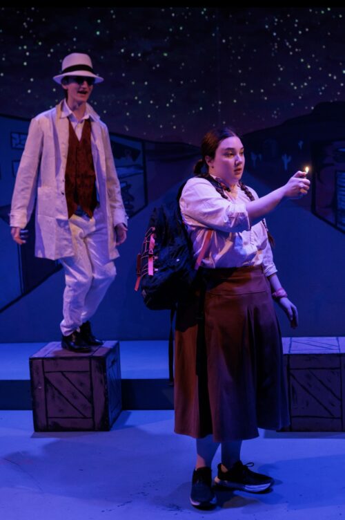 a person wearing a hat and jean vest holds out a pool cue like they are about to use it