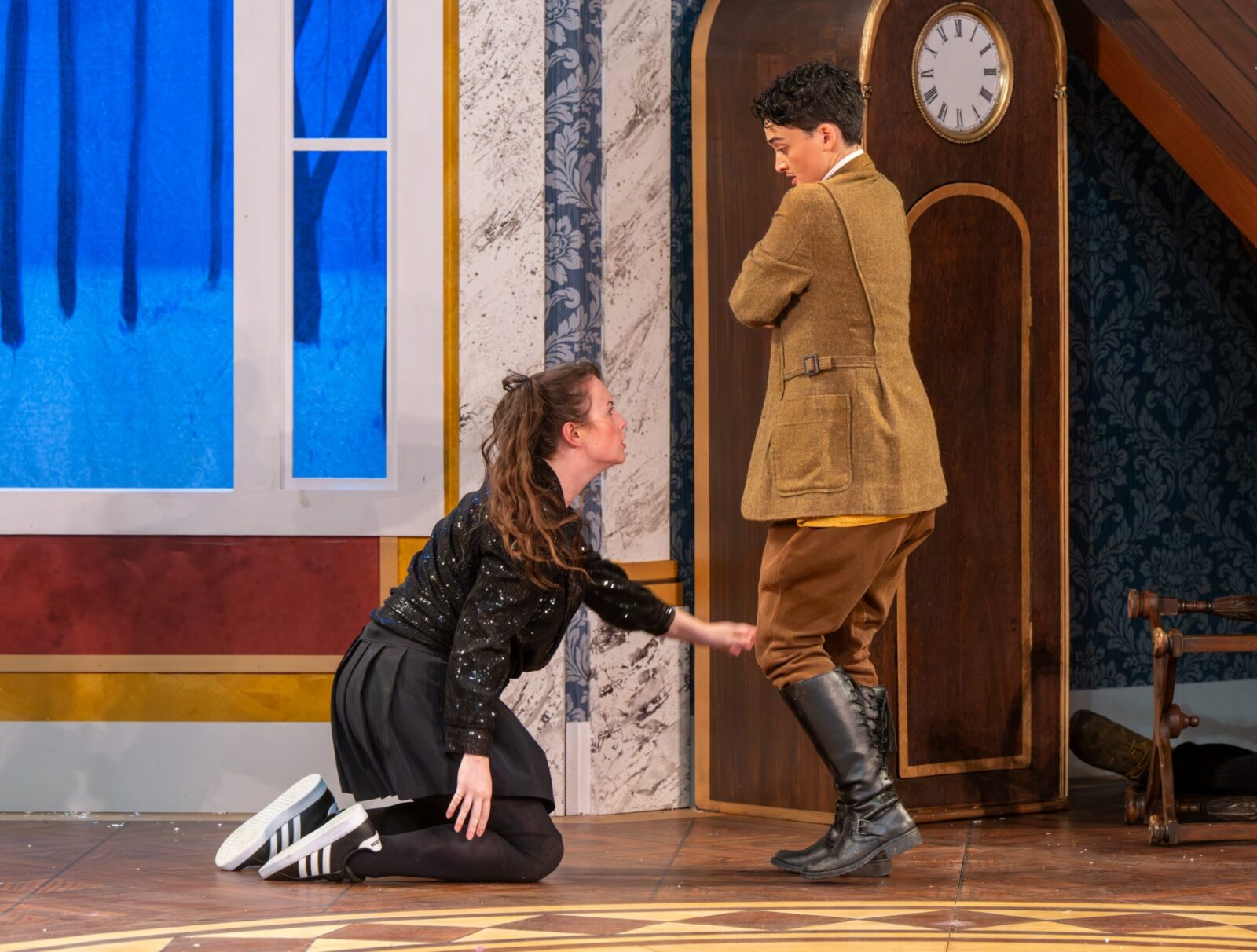 two people singing onstage together, on kneeling before the other