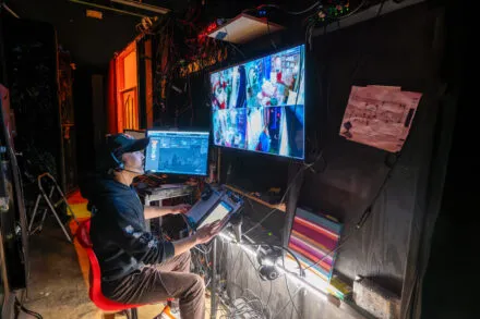 person sits in chair and looks at screen with images of stage scenes